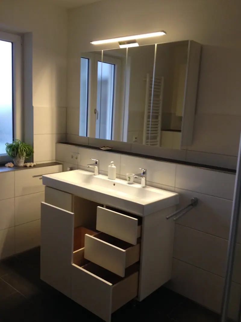 Badezimmer mit Waschtisch, Schubladen im Unterschrank und Spiegelschrank