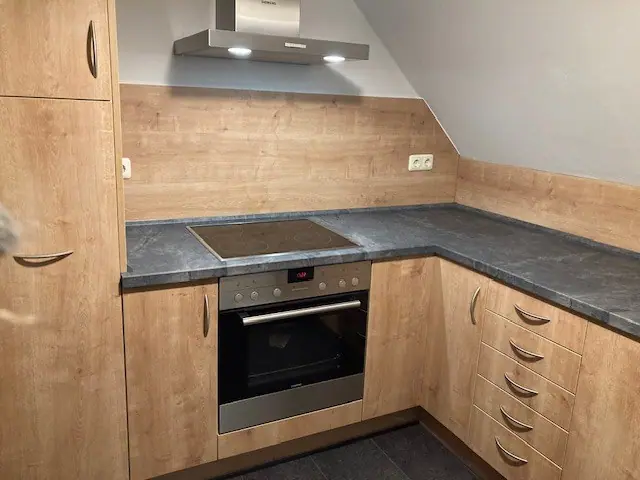 Küche mit Holzfronten und Dunstabzug unter einer Dachschräge